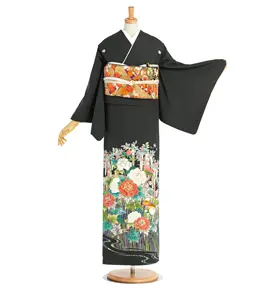 マネキンが、裾に鮮やかな花柄があしらわれた黒い着物を着ています。オレンジと金色の模様が入った華やかな帯も付いています。マネキンの腕が伸びて、着物の袖が際立っています。.