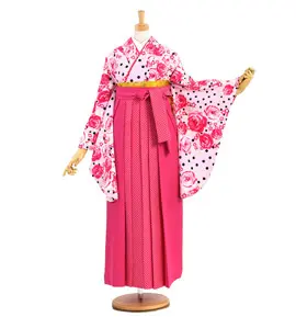 マネキンは日本の伝統的な衣装を着ています。花柄と水玉模様の着物にピンクの裾の付いたスカート、着物には赤とピンクの花が描かれ、裾には帯が結ばれています。.