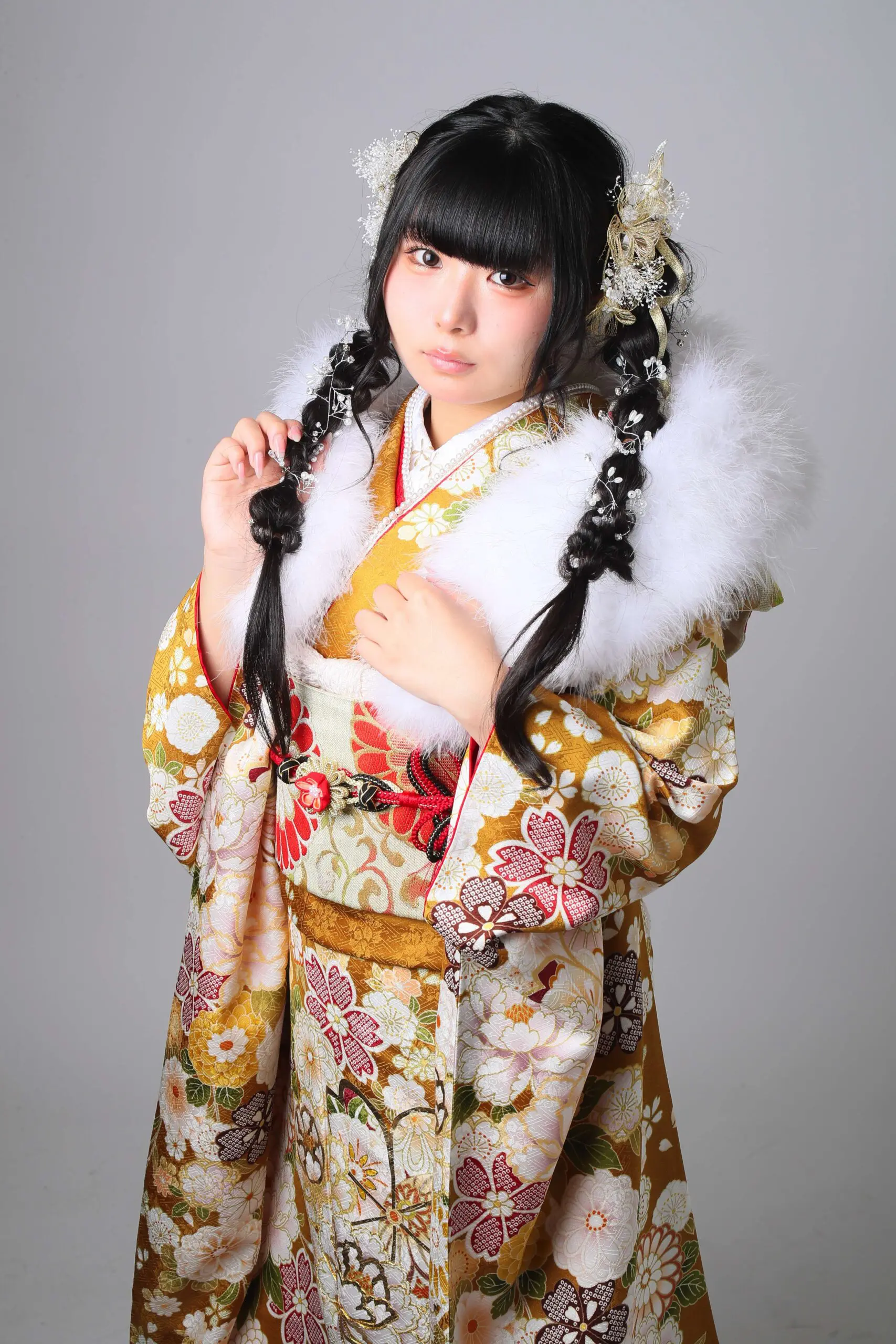 複雑な花柄があしらわれた日本の伝統的な着物と白い毛皮のストールを身に着けた人物が、無地の背景に立っています。長い黒髪は三つ編みにまとめられ、花飾りで飾られています。.