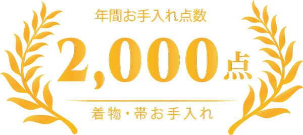 金色の月桂樹の枝で囲まれた日本語の文字と大きな数字「2,000」は、着物と帯の年間お手入れサービスが2,000回であることを示しています。.