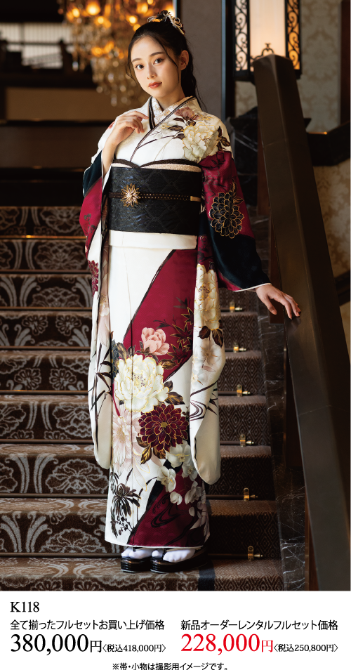 白、ワインレッド、黒の花柄の着物に金と黒の帯を締めて階段に立つ女性。下のテキストは、着物セットの購入価格とレンタル価格を日本語で表示し、商品コードK118を記載しています。.