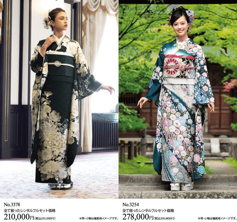 二人の女性が並んで立っており、それぞれが凝った花模様のフォーマルな着物を着ている。左側の女性は黒と白の着物を着ており、右側の女性は白地に青とピンクの花があしらわれた着物を着ている。.