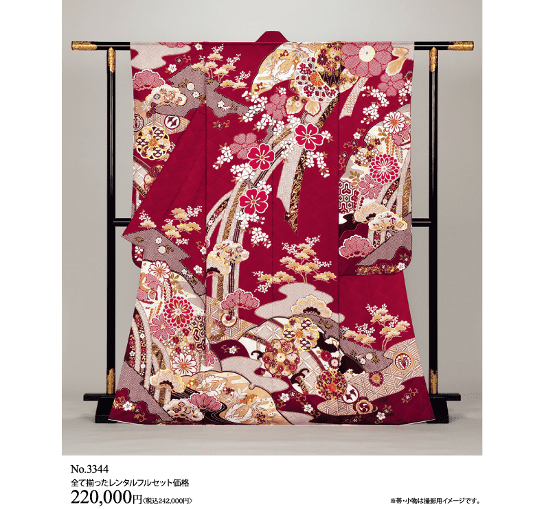 金、白、ピンクで複雑な花柄と幾何学模様が描かれた伝統的な赤い着物が、黒い木の台に飾られている。価格は左下に220,000円と表示されている。.