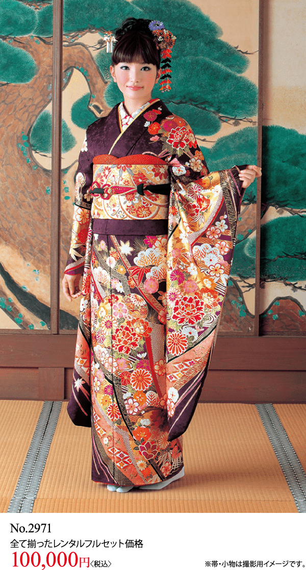 花模様の色とりどりの装飾が施された着物を着た女性が、室内で畳の上に立っている。髪には伝統的な髪飾りをつけている。背景には障子と塗り壁。下に洋服の値段の文字が見える。.