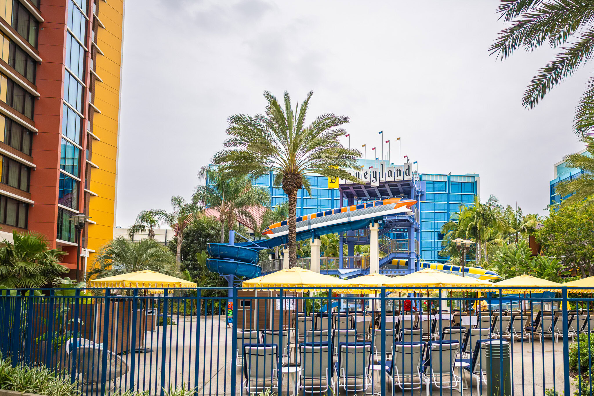 Disneyland Hotel with Monorail-themed water slide and palm trees surrounding the pool area.