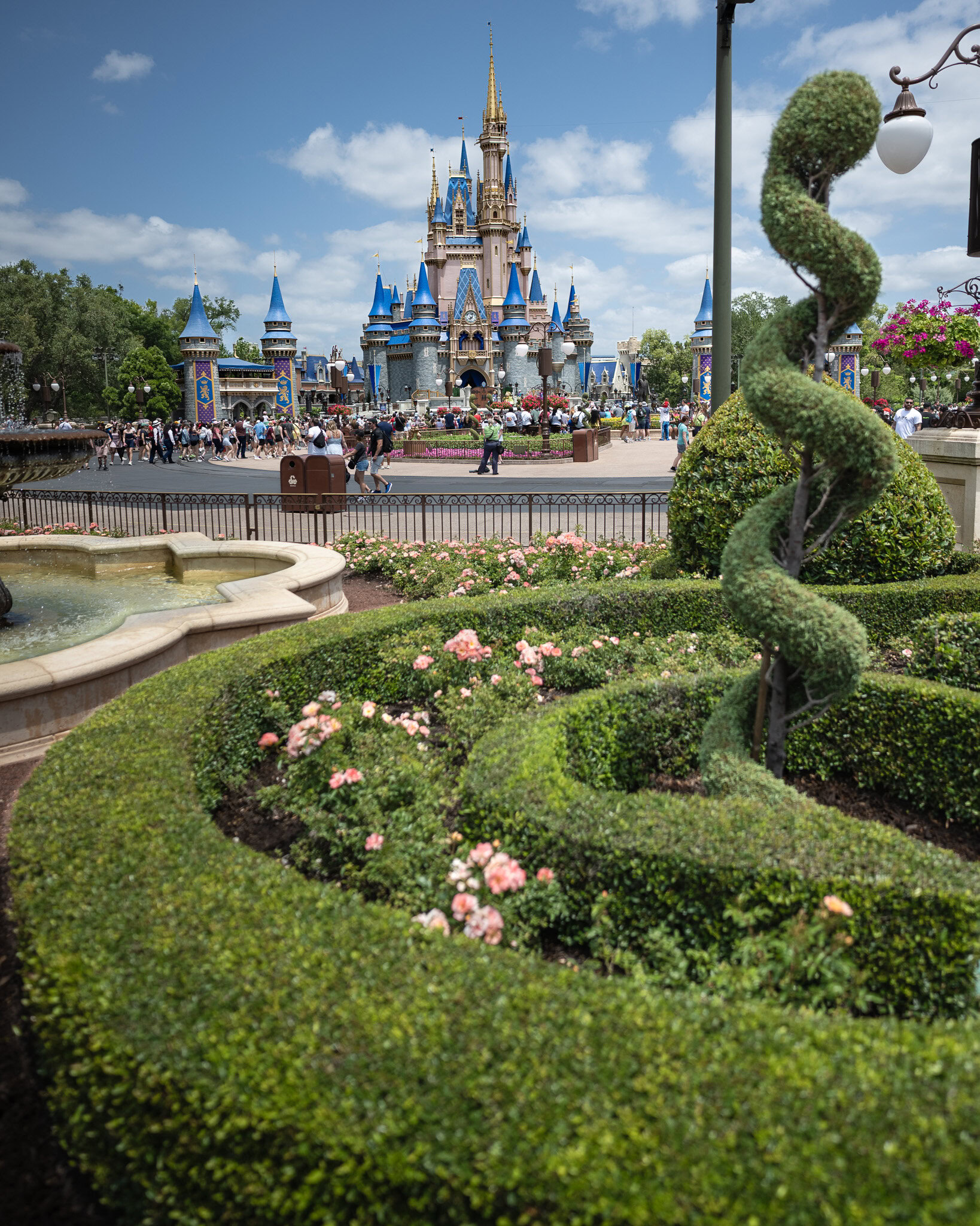 Cinderella Castle at Magic Kingdom with gardens and topiary in the foreground on a sunny day.