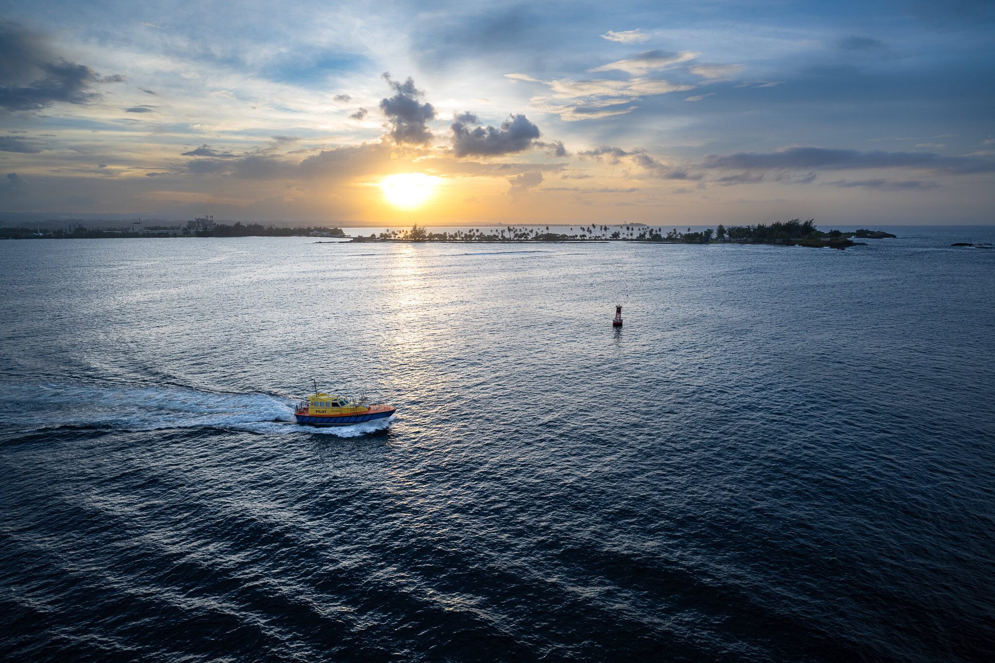 Pilot boat guiding the Disney Magic out of San Juan Bay at sunset during embarkation day.