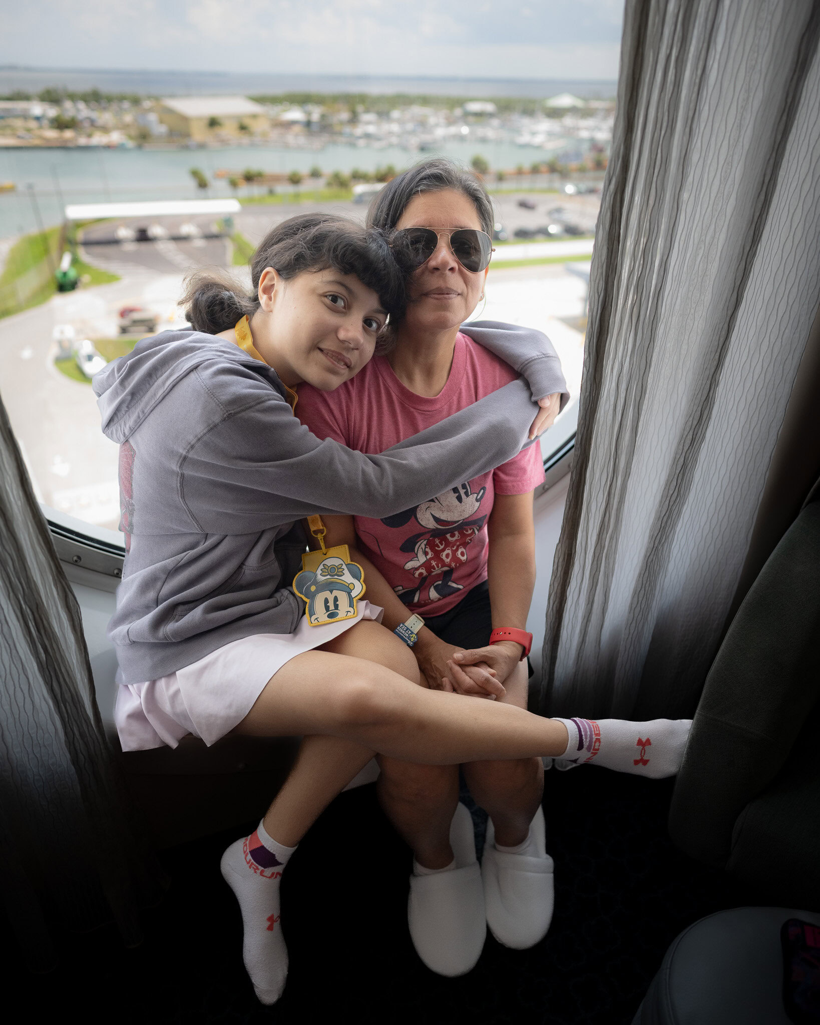 Daniela and Lucy smiling inside their Disney Wish Oceanview Stateroom.