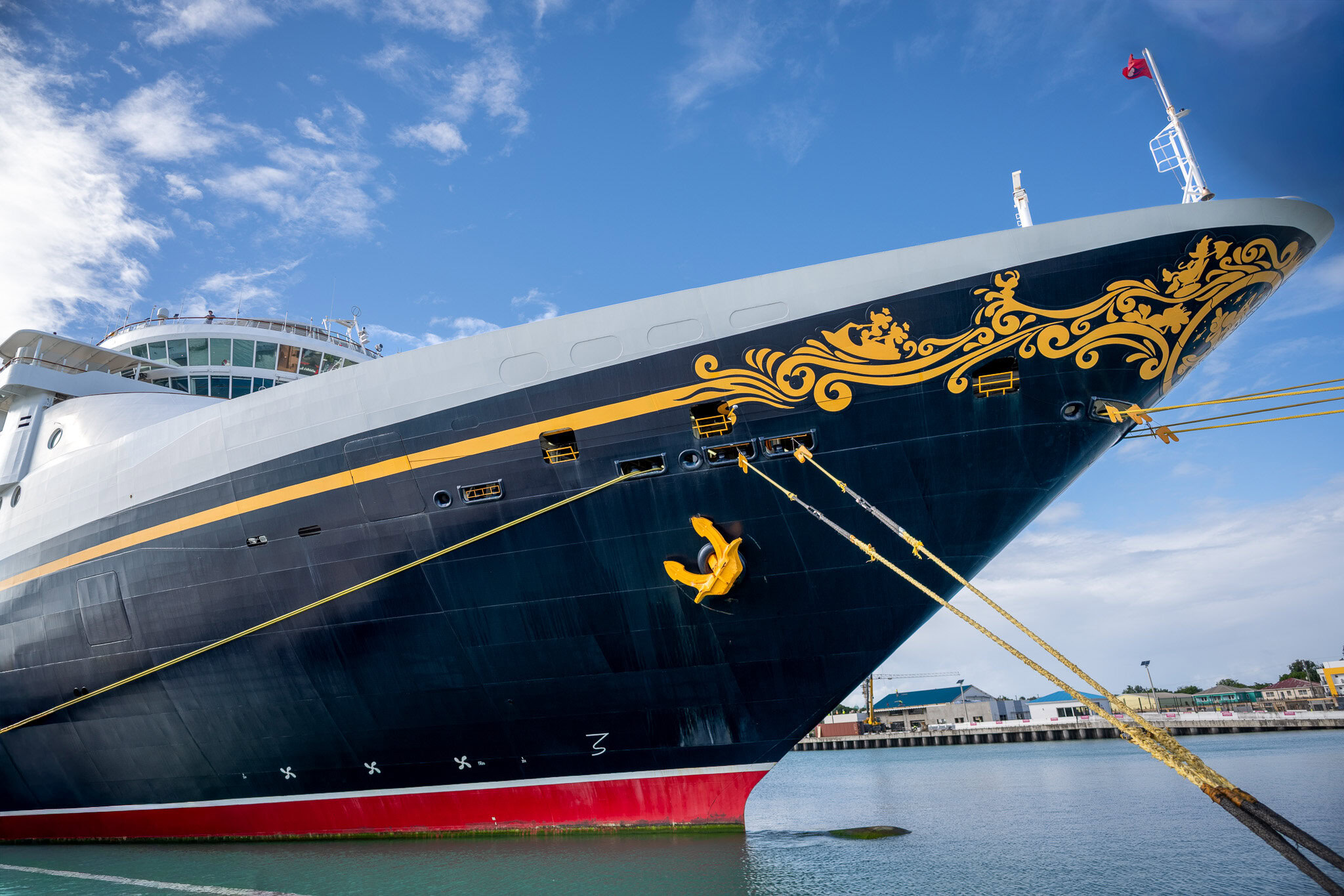 Disney Magic cruise ship docked in St. John’s, Antigua, photographed from a low angle with clear blue skies.