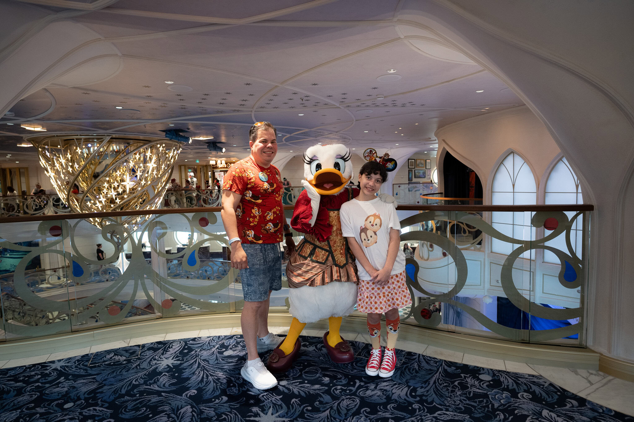 Raúl and Daniela posing with Daisy Duck in the Grand Hall of the Disney Wish.