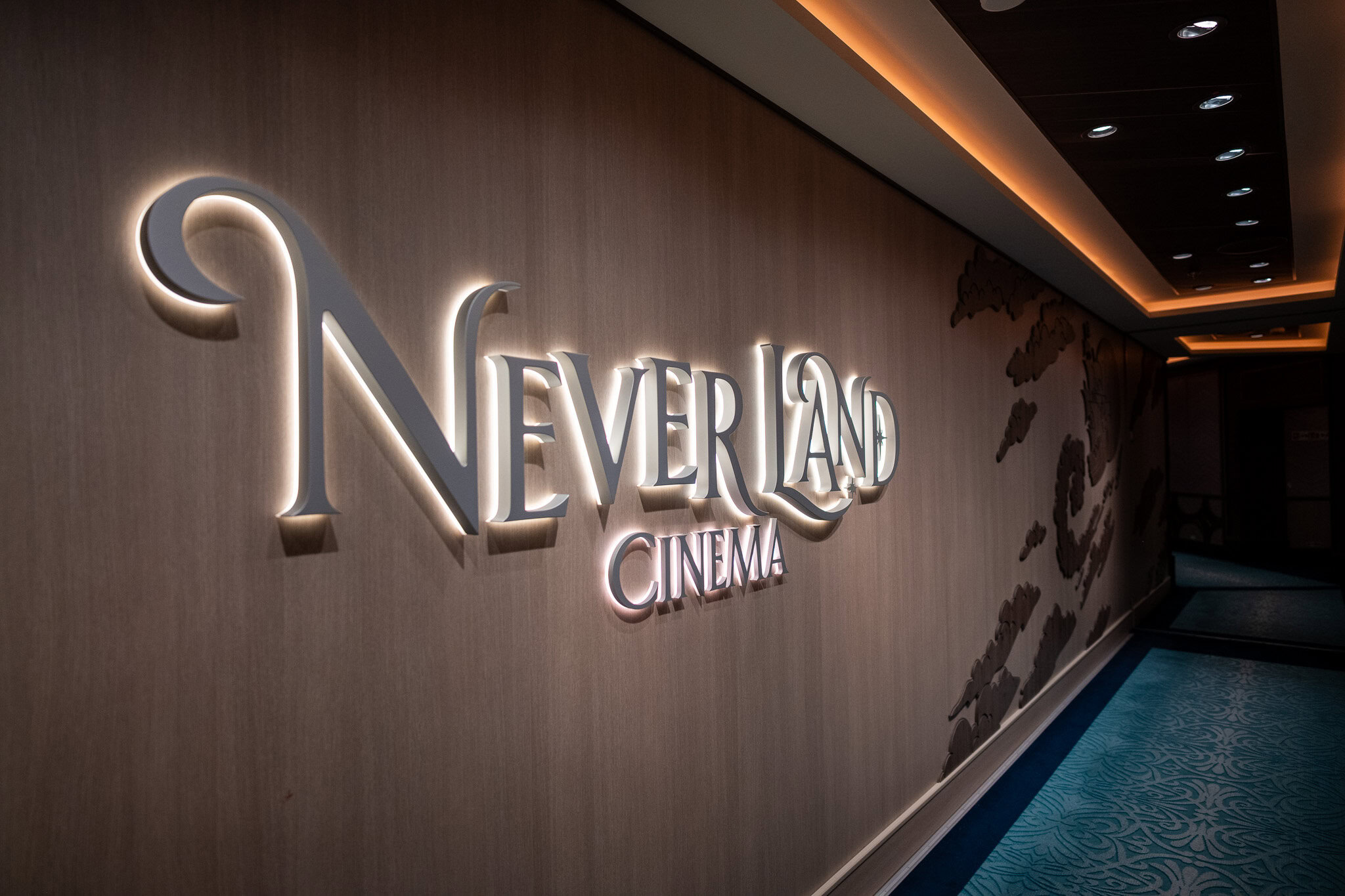 Illuminated Never Land Cinema sign in a themed hallway on the Disney Wish.