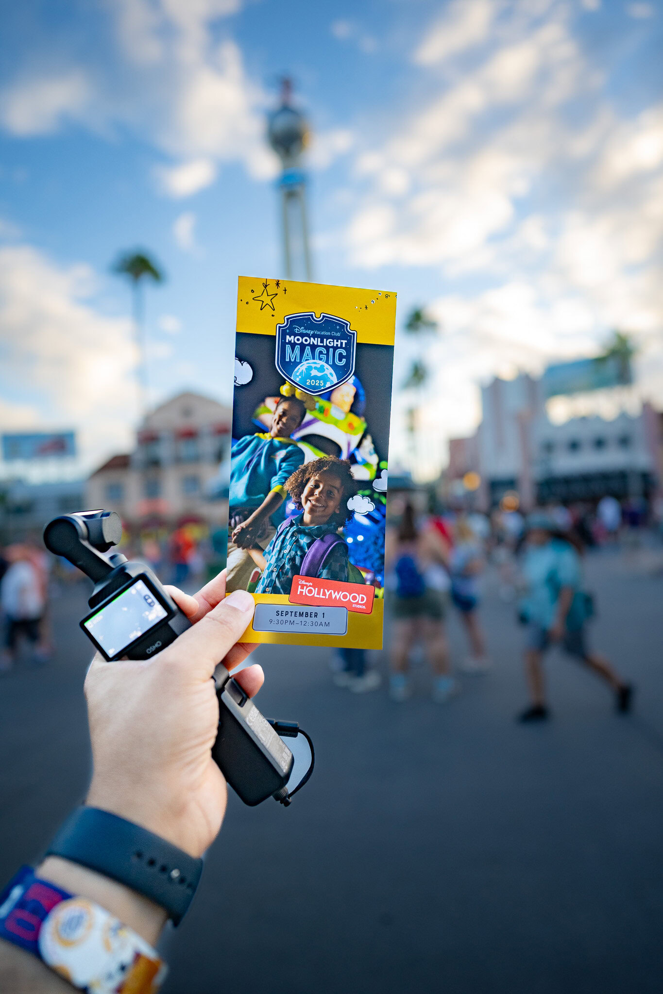 Guest holding 2025 Moonlight Magic event guide at Disney’s Hollywood Studios entrance