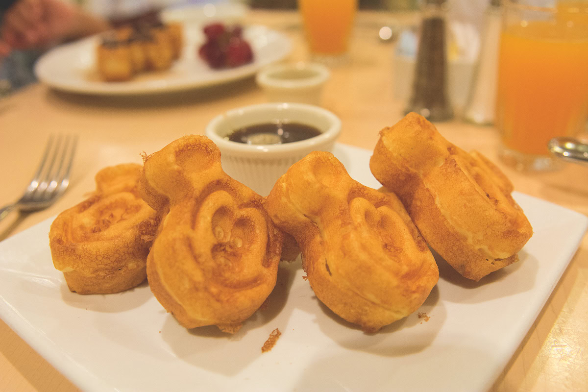 Un plato de waffles dorados en forma de Mickey servidos con almíbar en Walt Disney World.