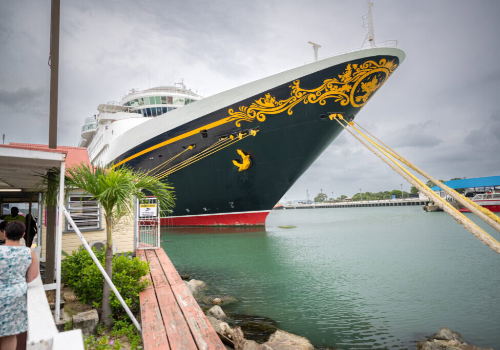 Disney Magic cruise ship docked at Antigua port with cloudy sky backdrop.