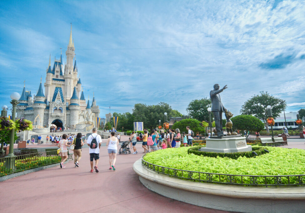 Los visitantes caminan hacia el Castillo de Cenicienta con la estatua de Walt Disney y Mickey Mouse a la vista en Magic Kingdom.
