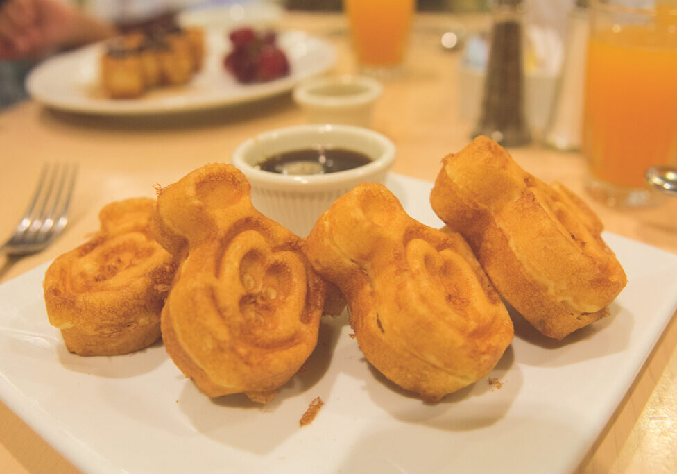 Un plato de waffles dorados en forma de Mickey servidos con almíbar en Walt Disney World.