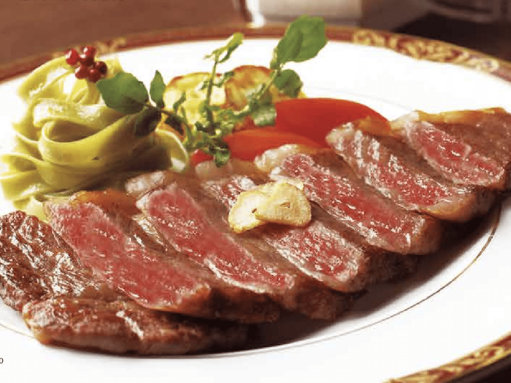 Sepiring steak dan sayuran di atas piring putih.