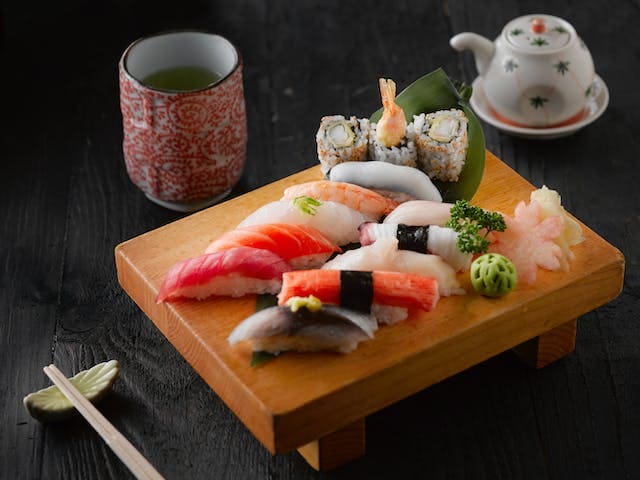 Sushi dan teh Jepang di atas papan kayu.