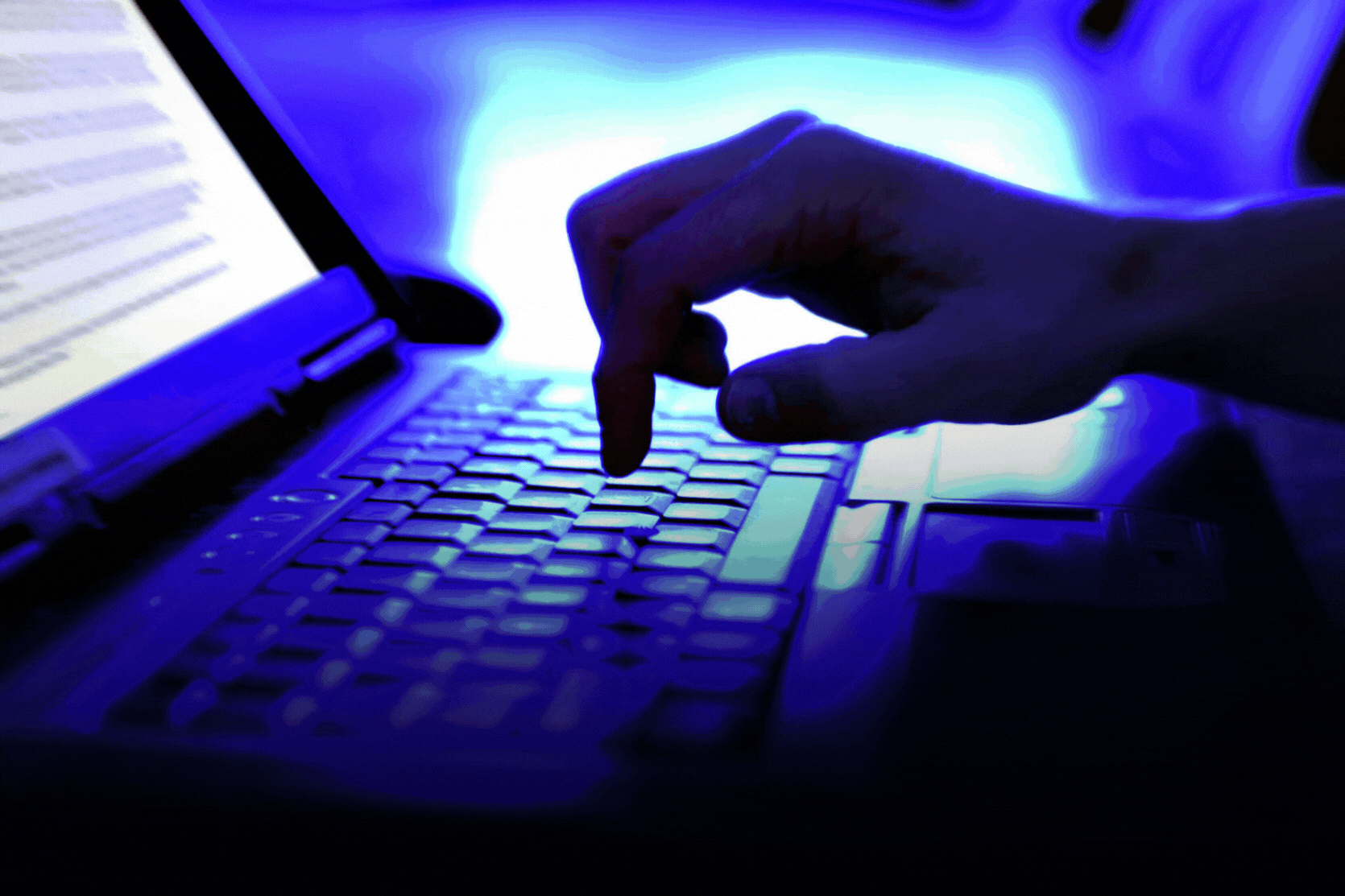 Pag-type ng kamay sa keyboard ng laptop na may text document na bukas sa screen na naiilawan ng asul na ilaw. Mag-ingat kapag lumipat sa online upang maiwasan ang pagkabiktima ng mga pekeng profile at nakatagong mga scammer scheme.