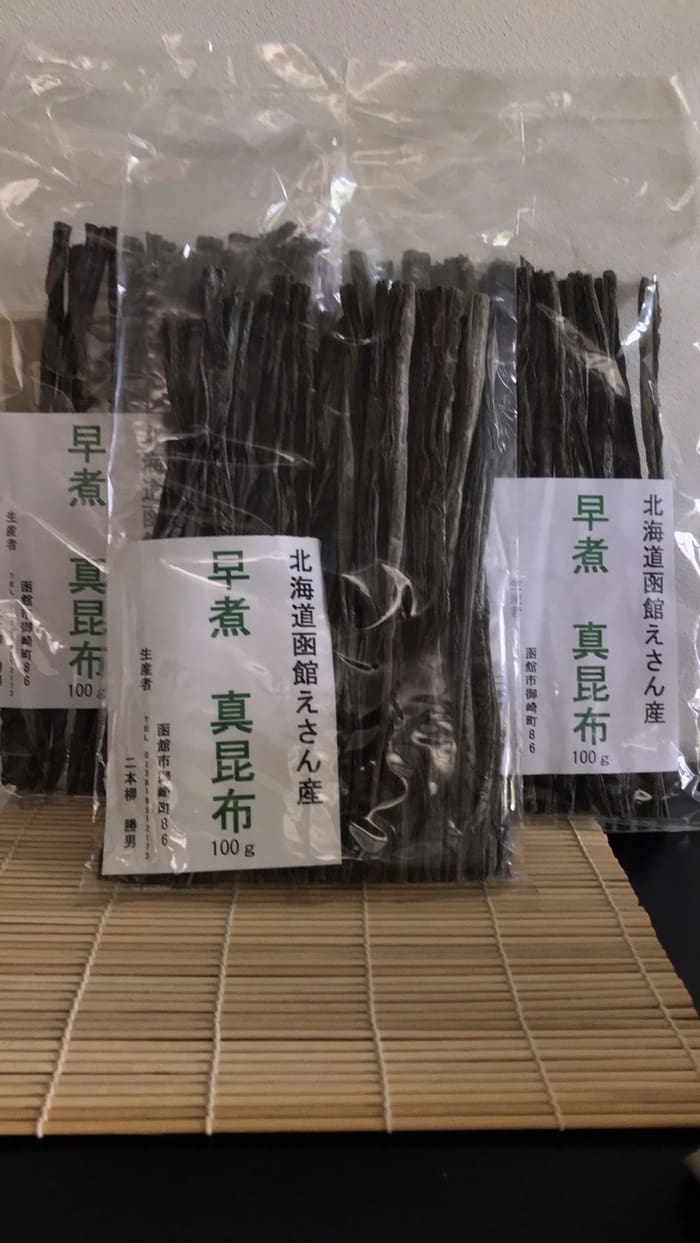 يتم ترتيب أكياس عشب البحر المجفف من Eyama ، Hokkaido ، في وضع مستقيم على حصائر الخيزران وتحمل ملصقات يابانية تشير إلى الأنواع الرائعة من عشب البحر المسلوق مبكرا.