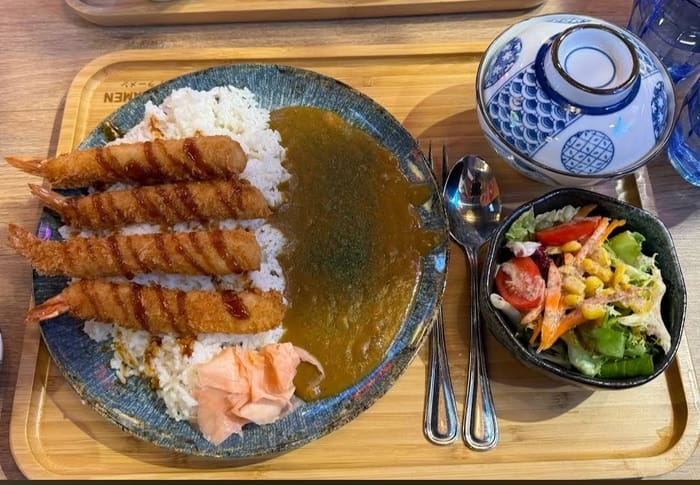 طبق من الجمبري بالبقسماط فوق الأرز مع صلصة الكاري والزنجبيل الأحمر والسلطة. حساء للأطباق الجانبية بملعقة.