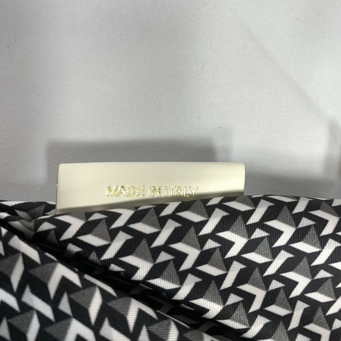 ROBERTA PIERIの黒と白の幾何学模様のミニダッフル生地に、金文字で「MADE IN ITALY」と書かれた白いラベルが貼られている。背景は白無地。.