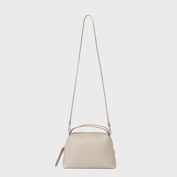 イタリア製ベージュレザーのクロスボディバッグ「GIANNI CHIARINI ALIFA」は、ミニマルなデザイン、長さ調節可能なストラップ、ショートハンドル、ファスナートップが特徴。.