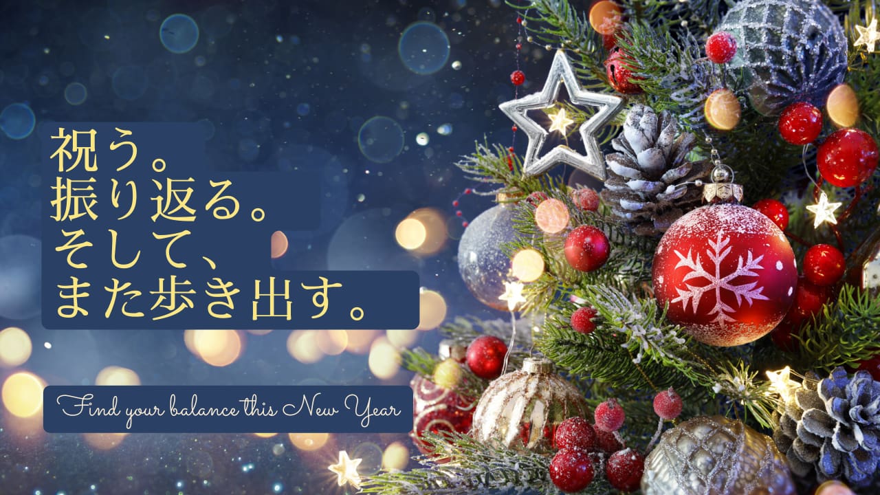 赤いオーナメントと銀色の星で飾られたクリスマスツリーが、「クリスマス」という金色の日本語の文字のそばに立っている。雪が静かに降っている。下の英語のメッセージは "Find your balance this New Year."。祝祭的で冬らしい雰囲気。.