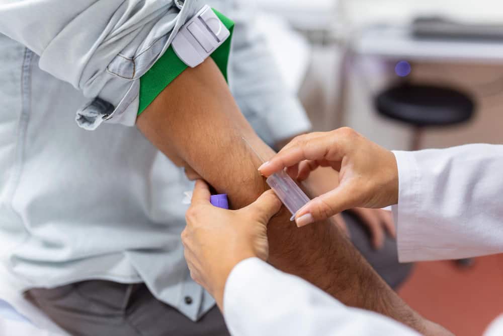 skilled focused young phlebotomy technician applying tourniquet male patient arm venipuncture