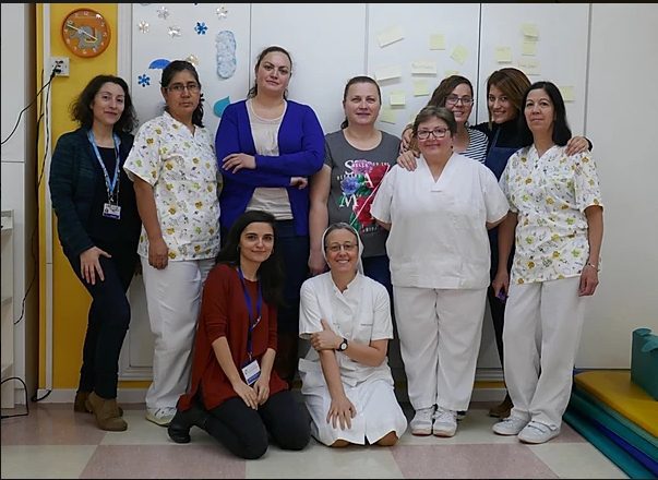 Palliative care, ten women, some in, pose together