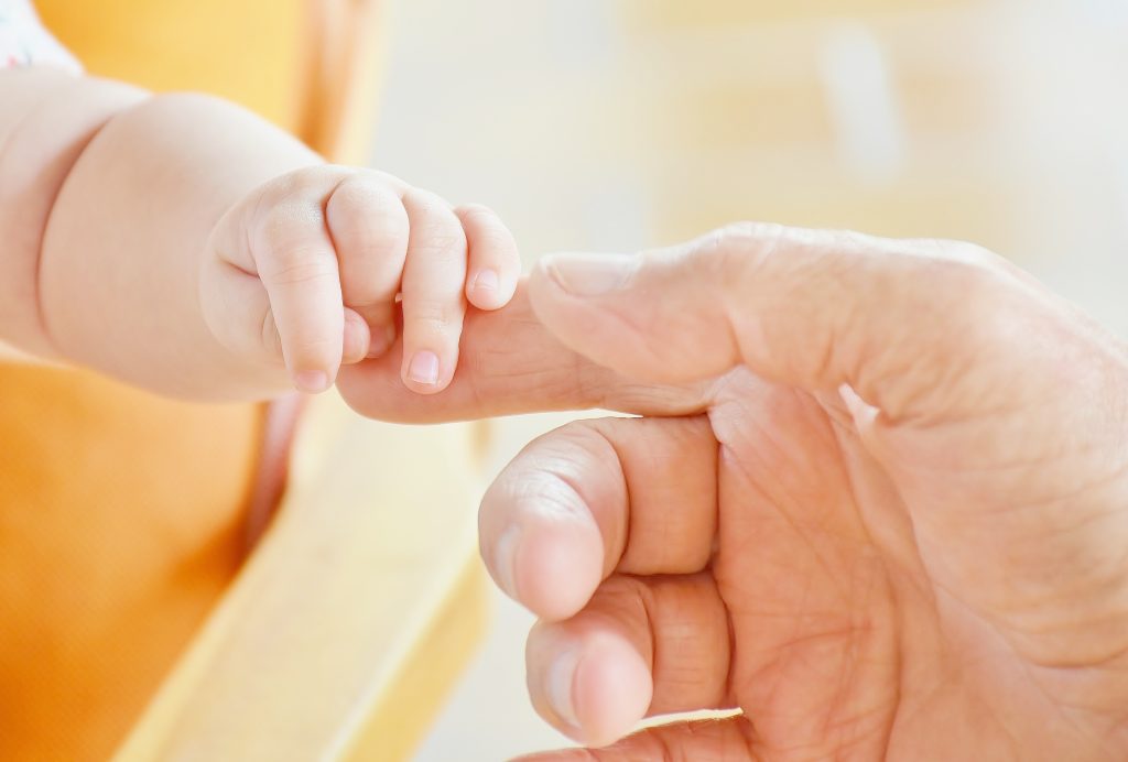 Paediatric palliative care Madrid A baby's hand clinging to an adult's finger symbolises the care and support of CAPPI Foundation becauseThey live in paediatric palliative care. CAPPI Porque Viven Foundation