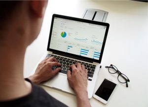 Man uses Google Analytics on laptop to analyze website traffic and conversions and generate insights.
