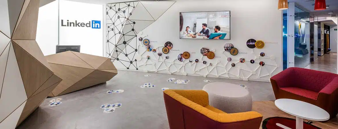Receção e área comum do projeto LinkedIn com design corporativo, balcão geométrico, mobiliário de espera e elementos gráficos integrados na parede.