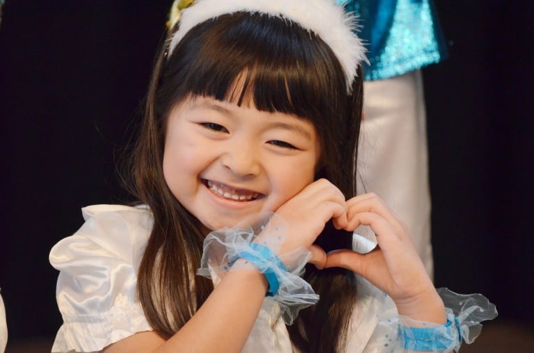 Little girl posing with a heart next to her face
