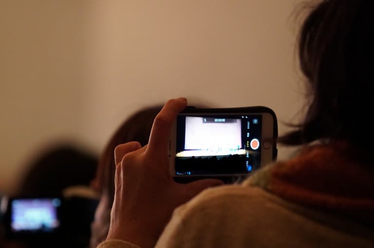 舞台をスマートフォンで撮影する母親