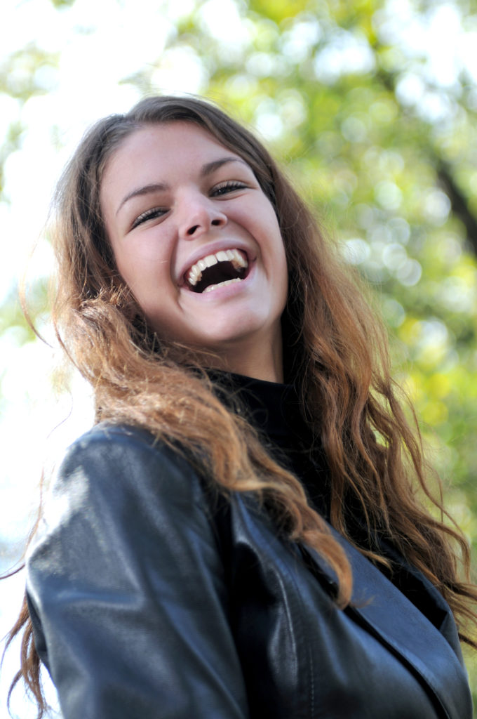Mujer joven riendo con follaje en el fondo