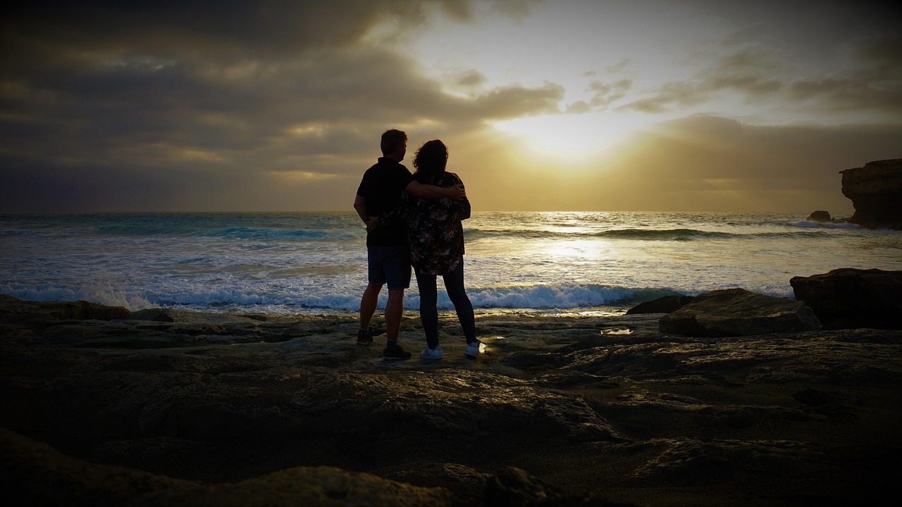 夕焼けの中、肩を寄せ合う男女の恋人