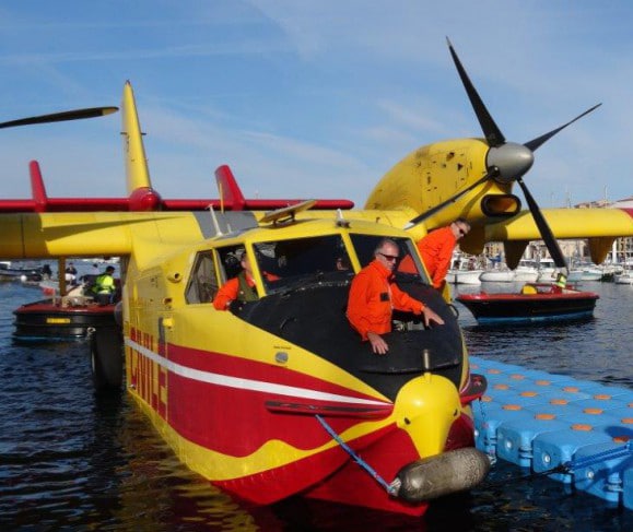 Two men standing next to a yellow and red plane during a raid.