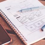 A mobile phone and laptop on a wooden table - inspiration for the next website builder.