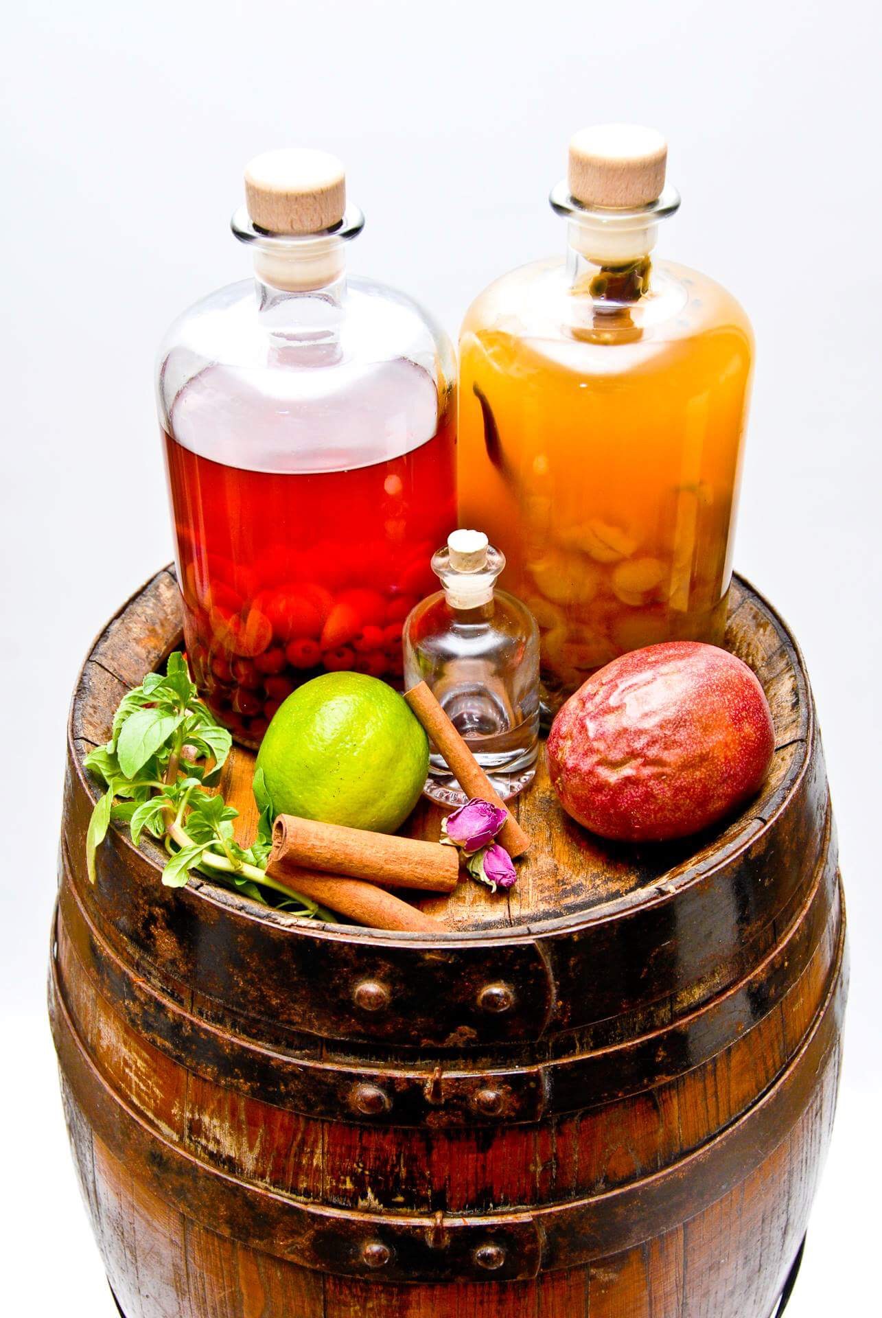 A wooden barrel with a bottle of liqueur, fruit, and spices.