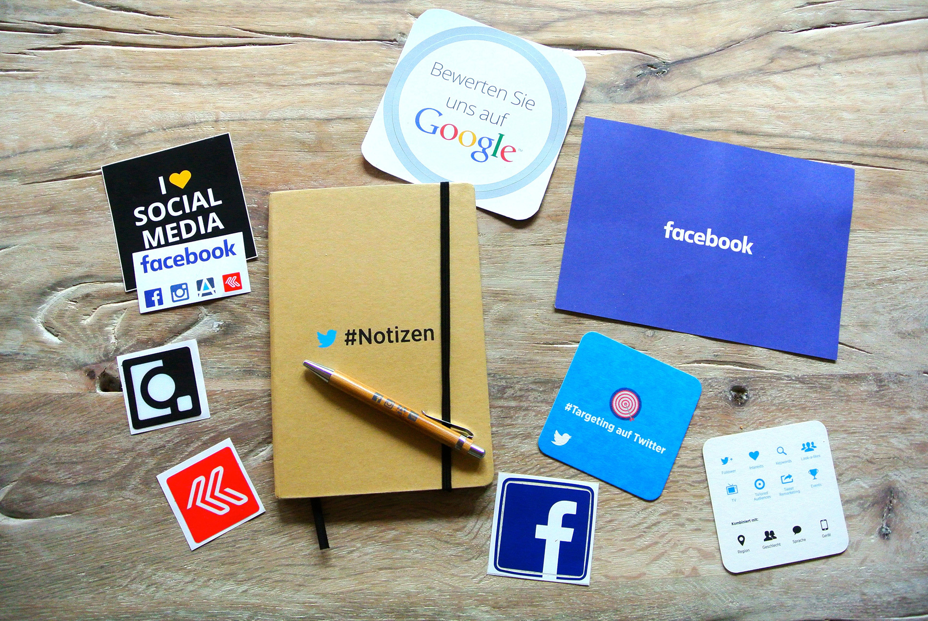 A notebook, pen, and social media stickers on a wooden table.