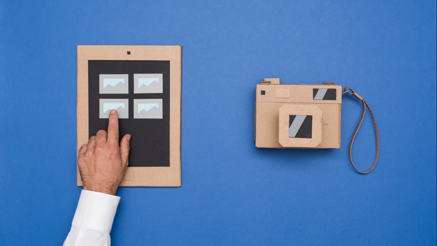 A man points a camera in front of a blue wall.