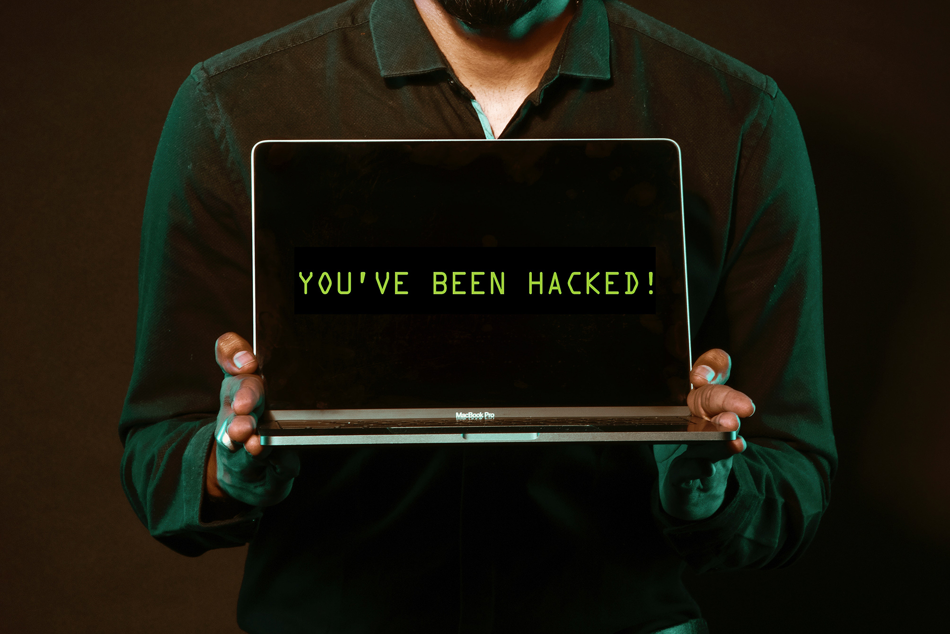 A man holding a laptop displaying an alert message indicating a successful WordPress attack.
