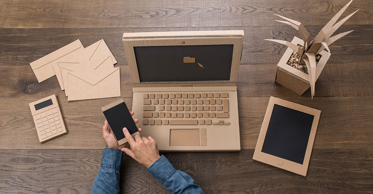 Amelia is multitasking with her laptop and mobile phone on a wooden table.