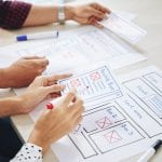 Two people sitting at a table with paper and pencils while discussing SEO strategies.