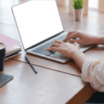 A woman typing on a laptop at a desk while using Convertio.co.