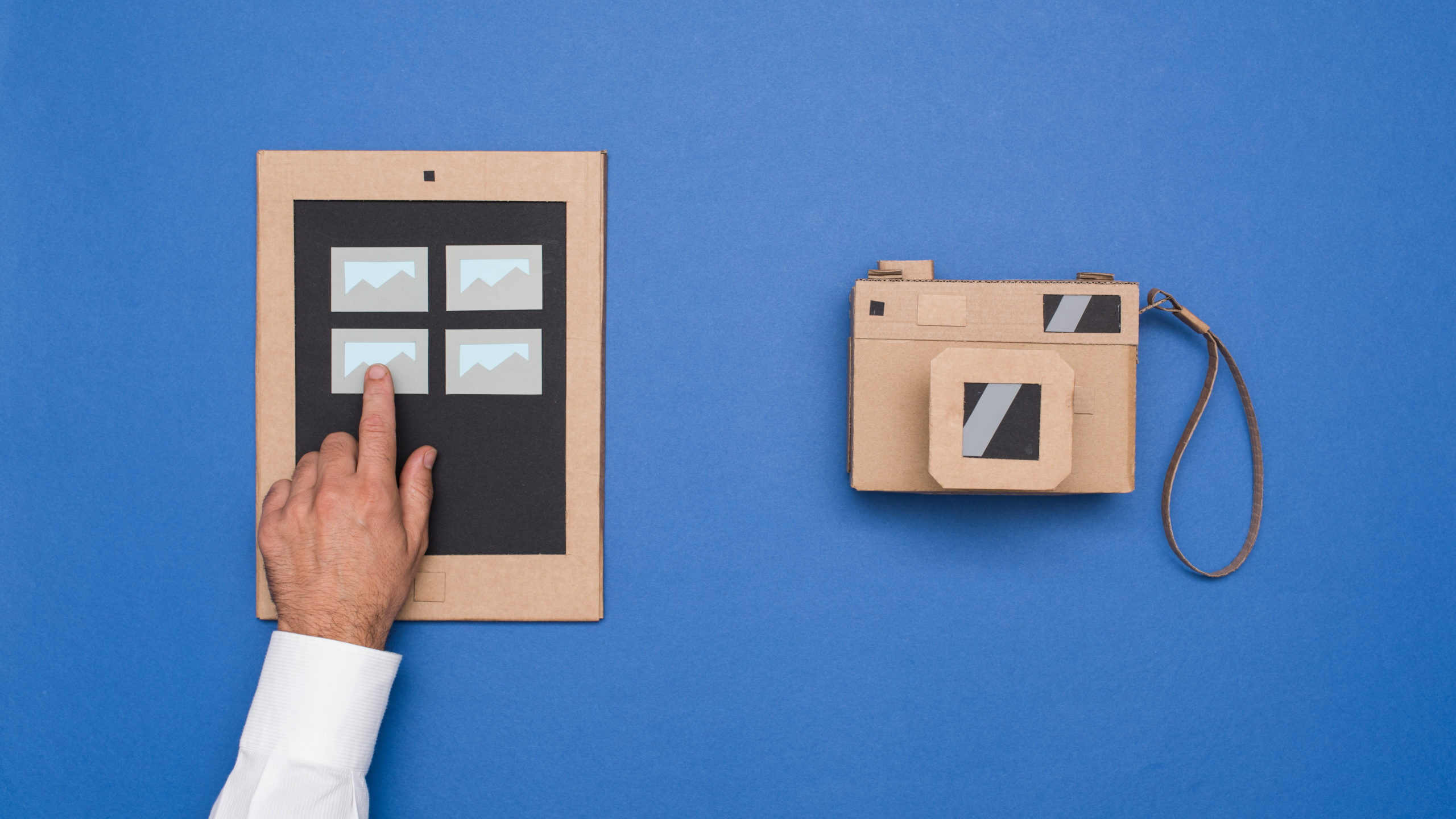 A man points to a phone and camera, capturing images for his photo library on Unsplash.