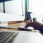 A person optimizing web accessibility by typing on a computer at a desk.