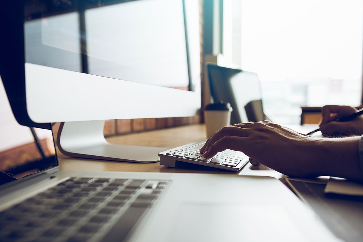 A person optimizing web accessibility by typing on a computer at a desk.